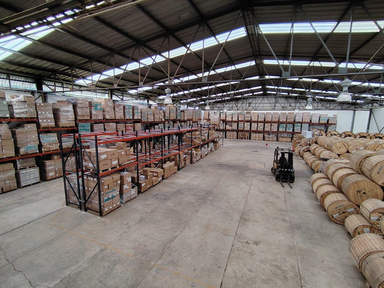 Bodega propia de Comcast Group con inventario en rack y carretes de cable