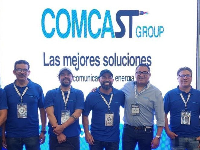 Equipo de Comcast Group frente al muro de marca - Comcast Group